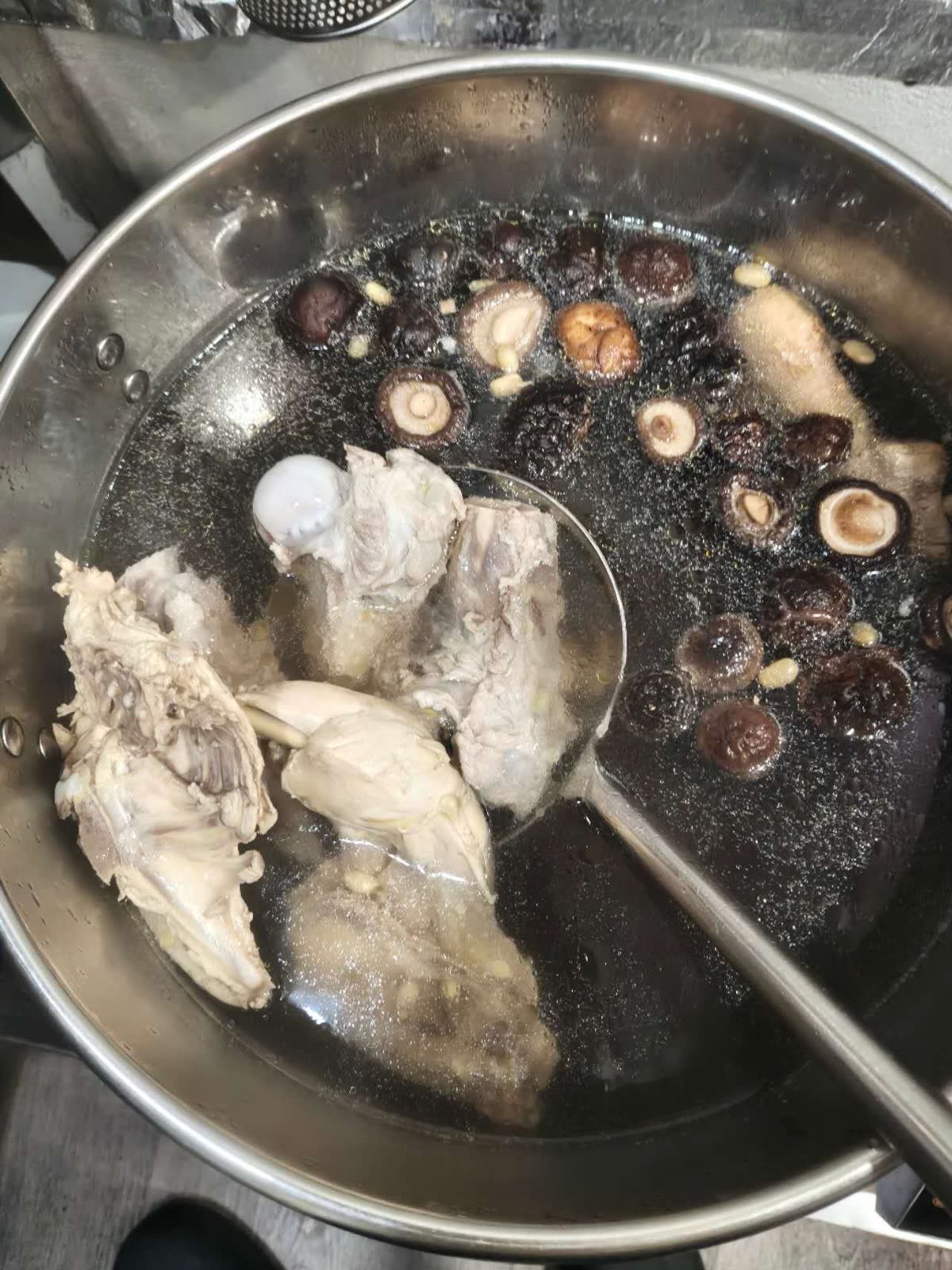 You Yi’s bone stock simmering with chicken and shiitake mushrooms.